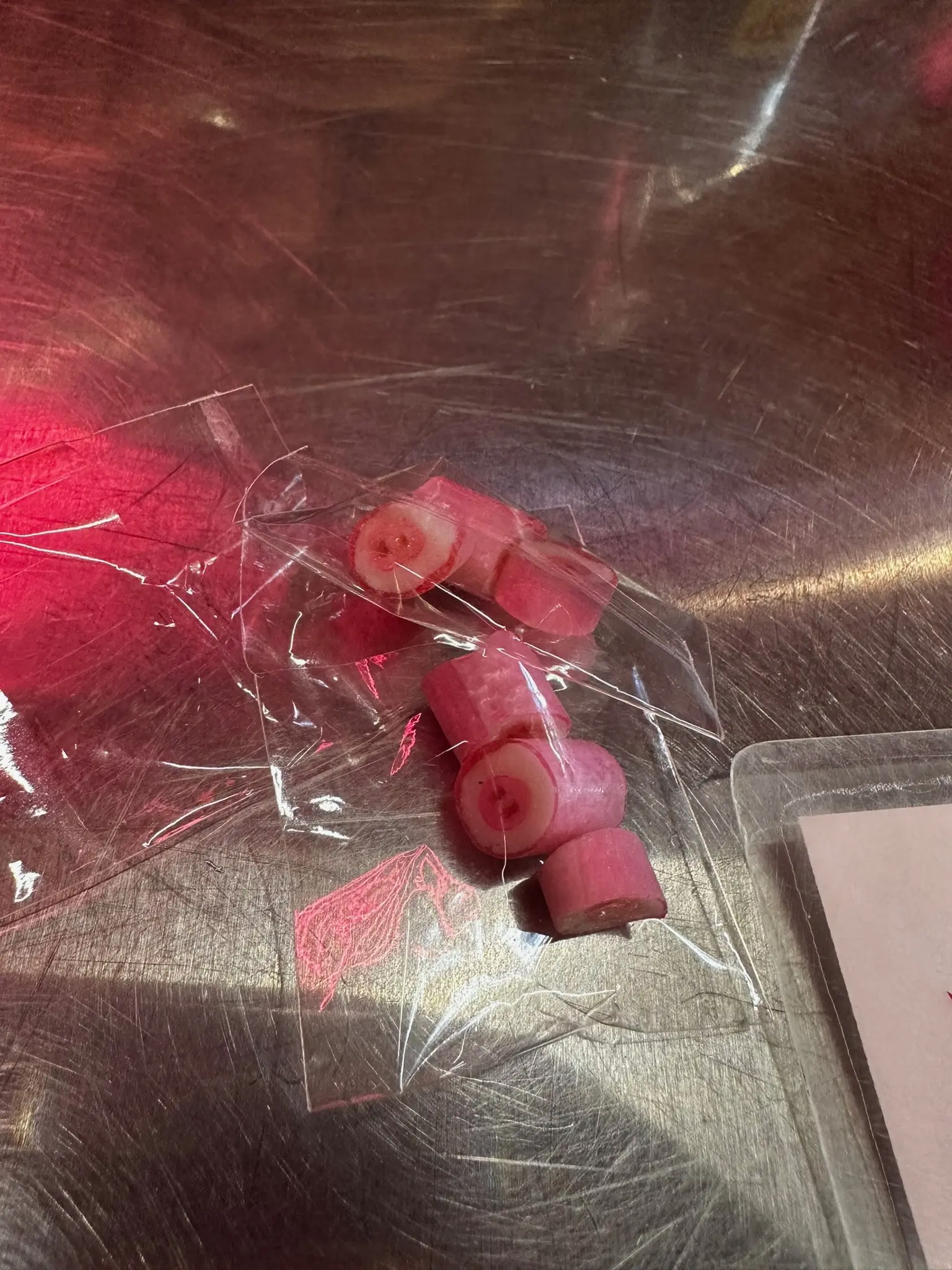 A small clear plastic bag of pig-snout shaped candies on a silver metal table.