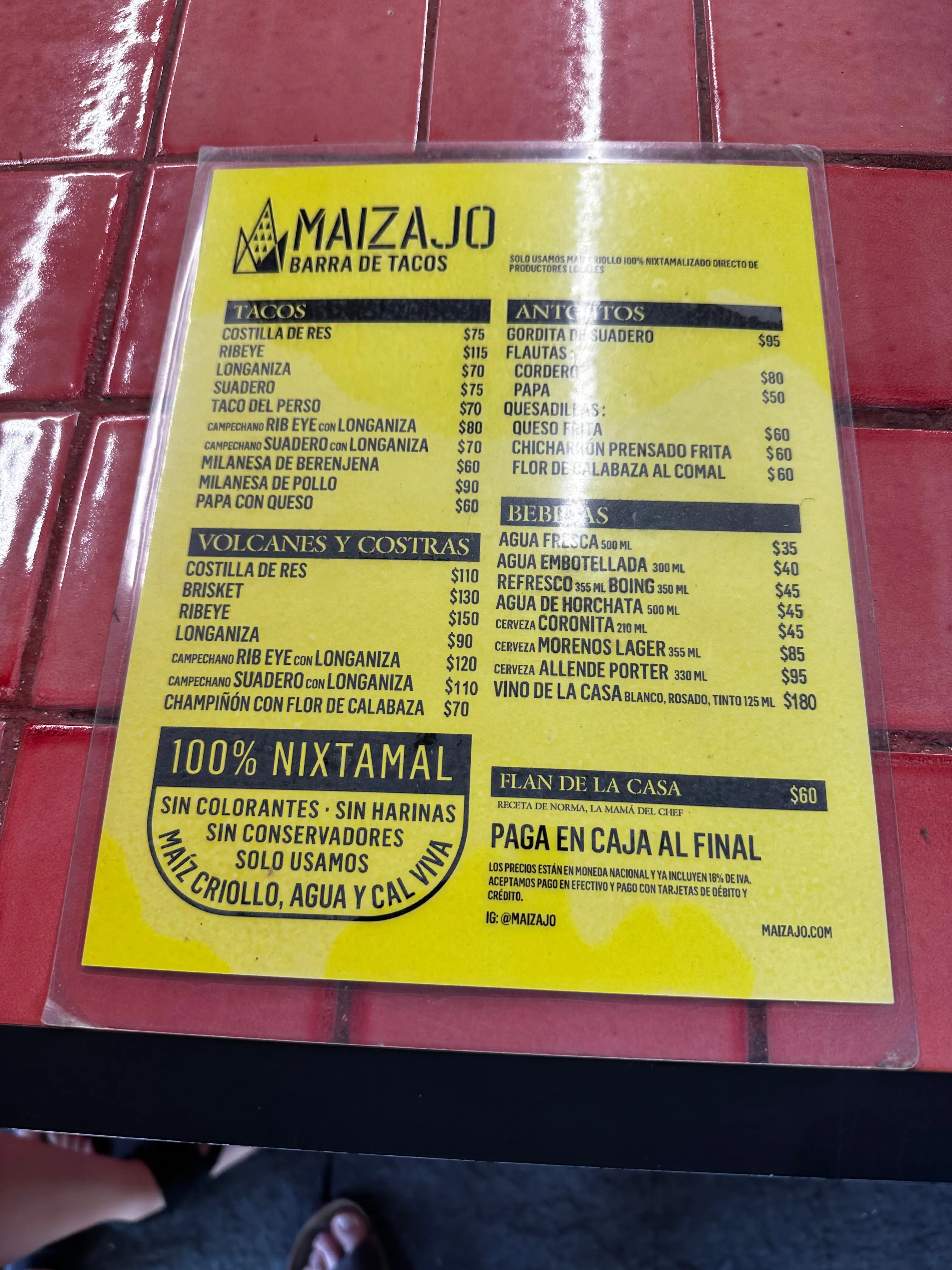A yellow, laminated menu for the Maizajo taco bar with the options and prices printed in black text.